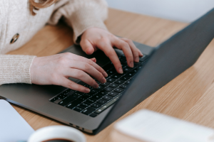 Close up image of hands typing on a black laptop's keyboard